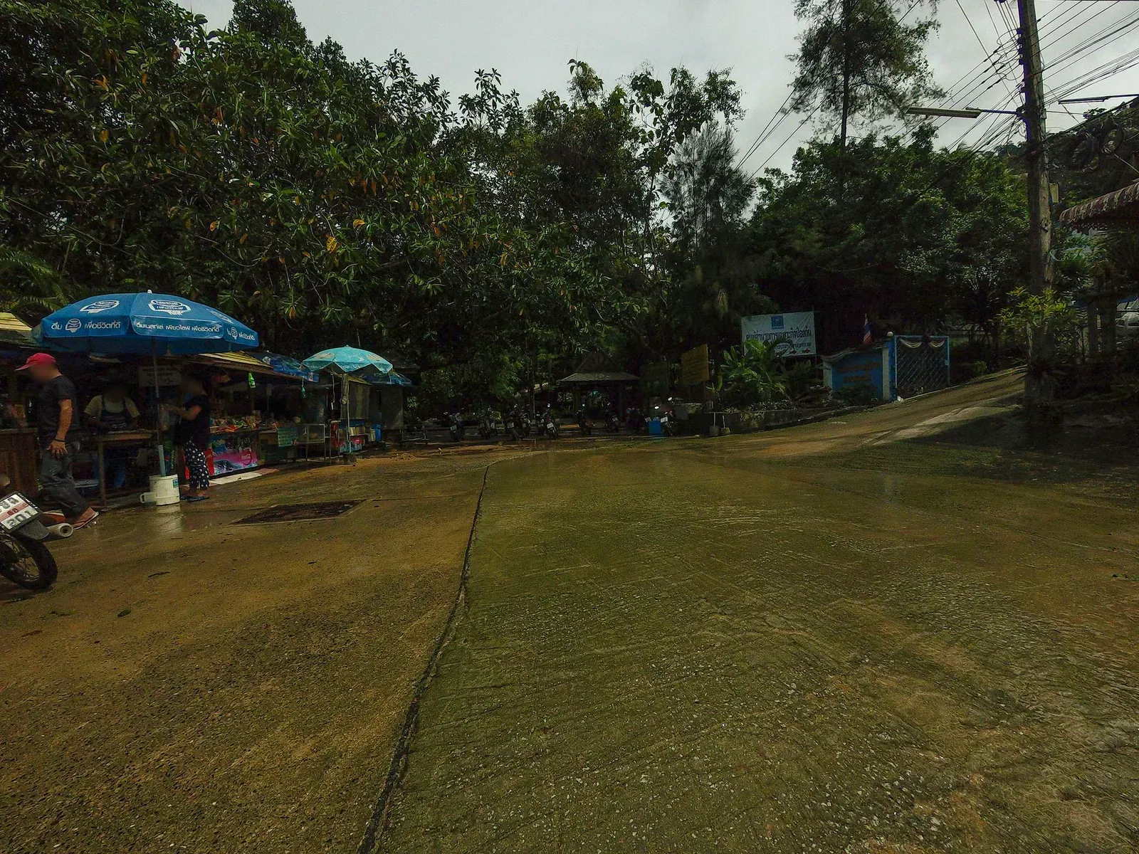 Roadside food stalls and umbrellas near the Hin Lad trailhead entrance
