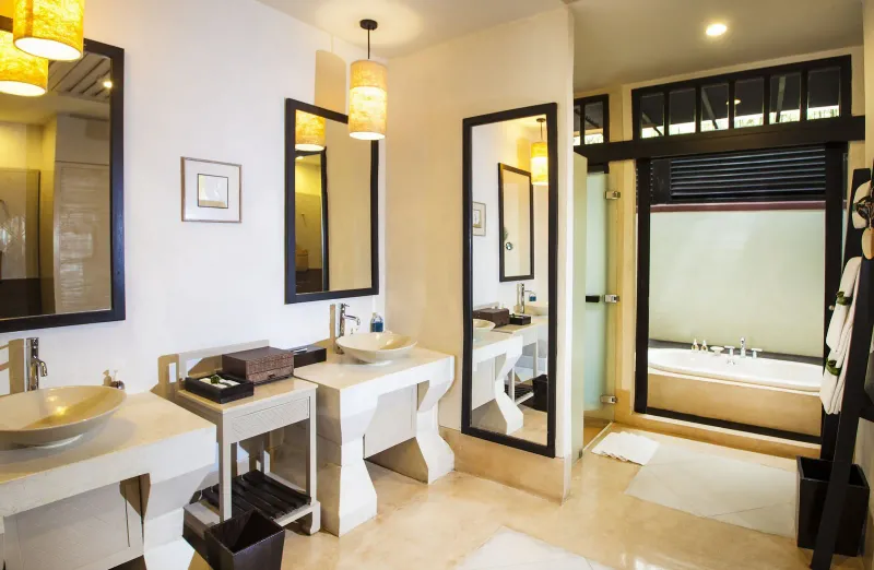 Suite bathroom with twin basins, mirrors and a glass-fronted tub area at Melati Beach Resort