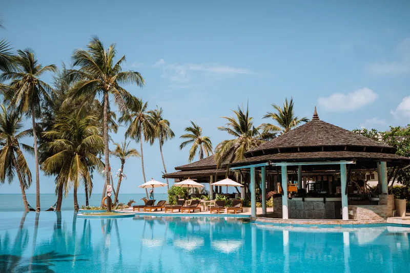 Melati Beach Resort infinity pool with a thatched pool bar pavilion and palms above the bay