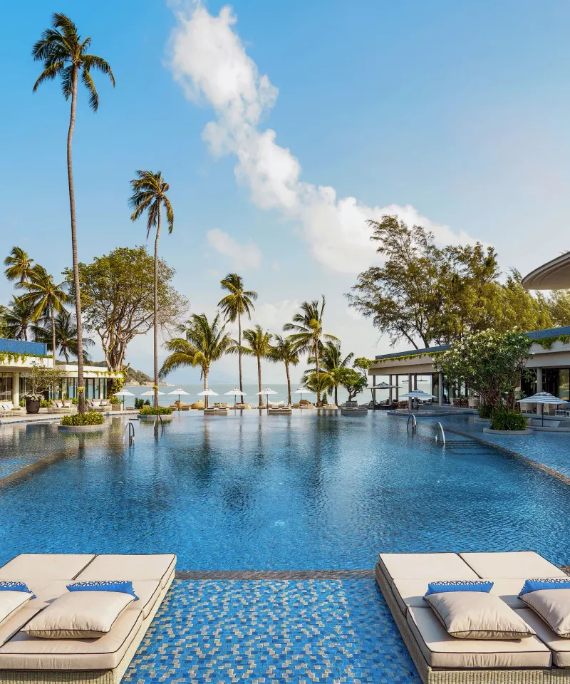 Melia Koh Samui pool with sunbeds, tall palms and beachfront restaurants facing the bay