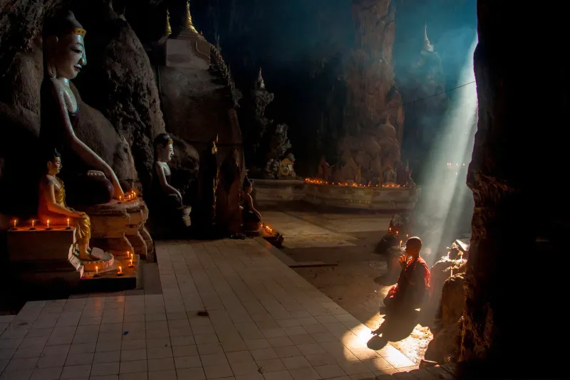 Light falling into a cave shrine where a monk sits
