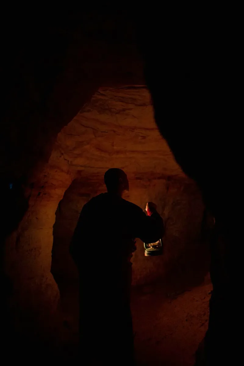 Silhouette of a monk standing in a shaft of light inside a cave