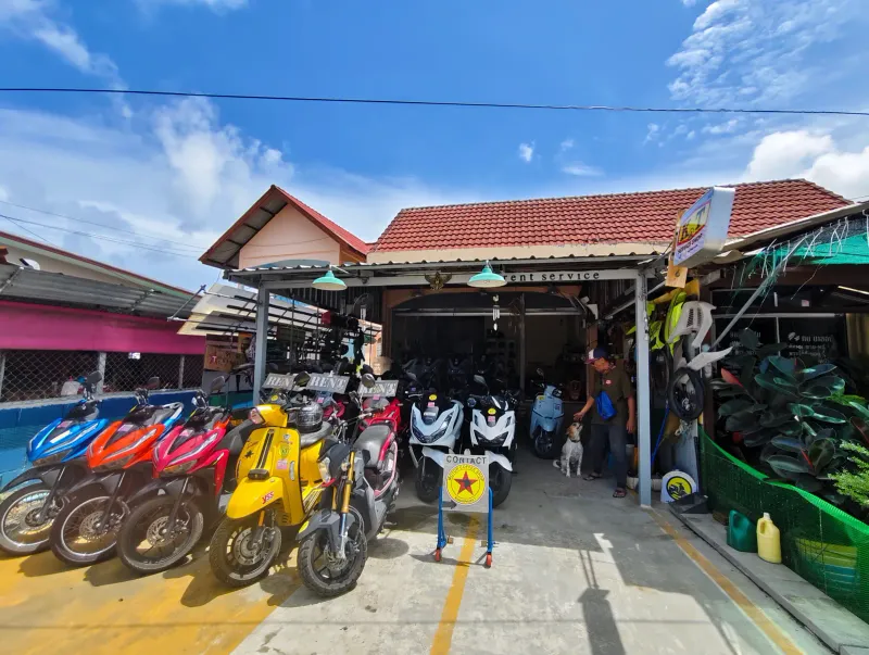 Thai scooter rental forecourt with rows of colourful automatic scooters under a tiled roof