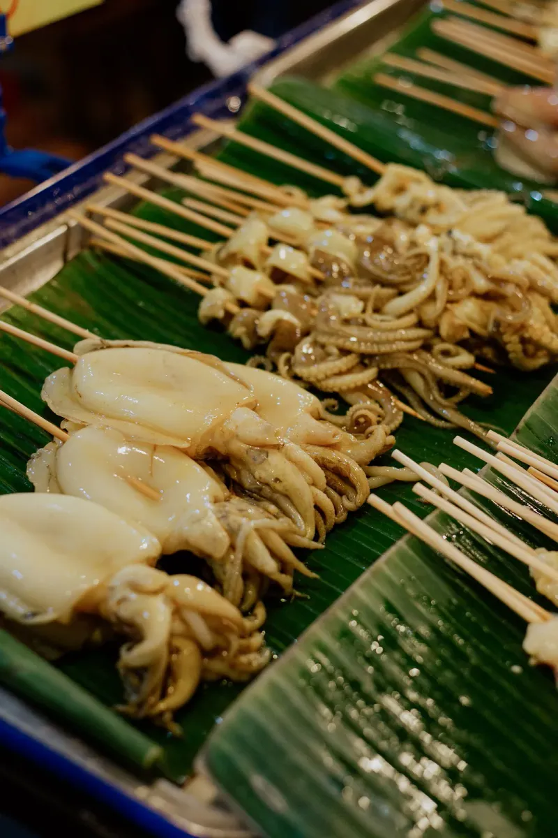 Grilled squid skewers on a banana leaf