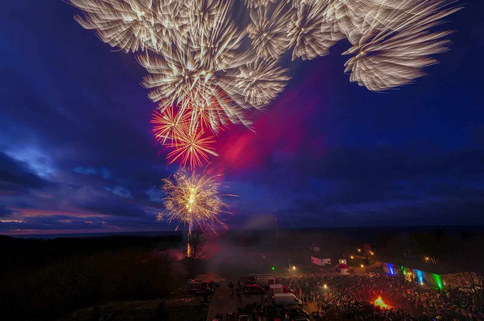 Fireworks over a dark coastline at night