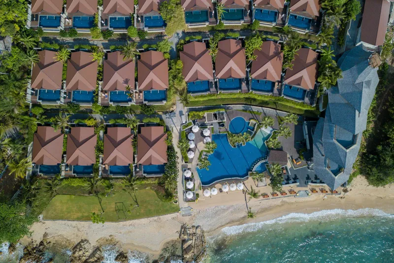 Aerial view of Nora Buri Resort pool villas above a stony shoreline and small beach pool