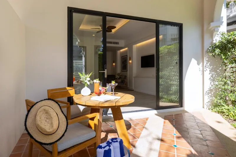 Ground-floor terrace with cane chairs, a round table and sliding glass doors at Outrigger Koh Samui