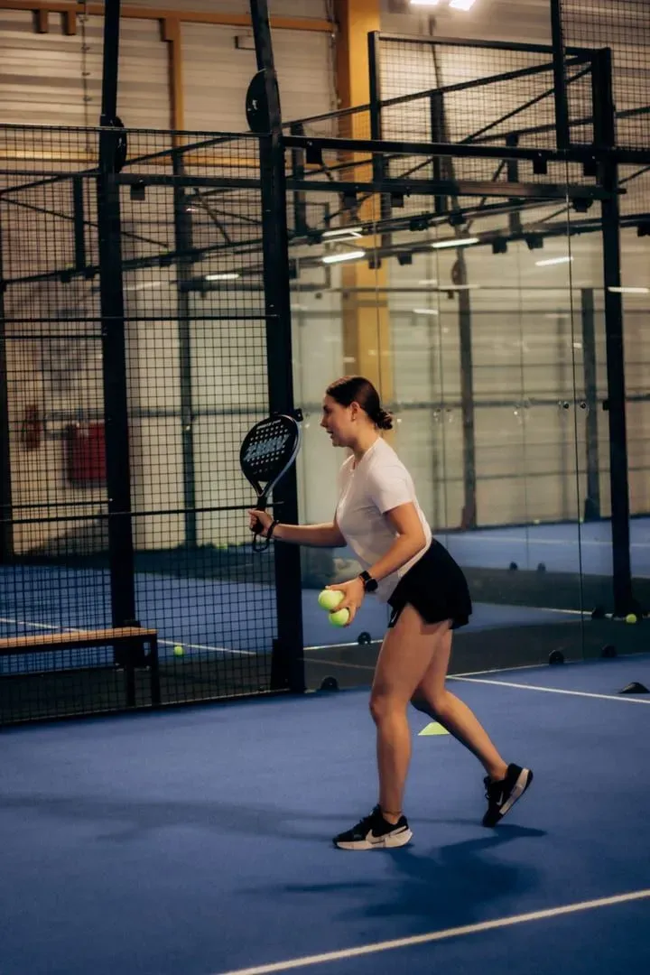 Player holding a padel racket and ball courtside before a match, the covered-court setup at Padel Paradise Lamai