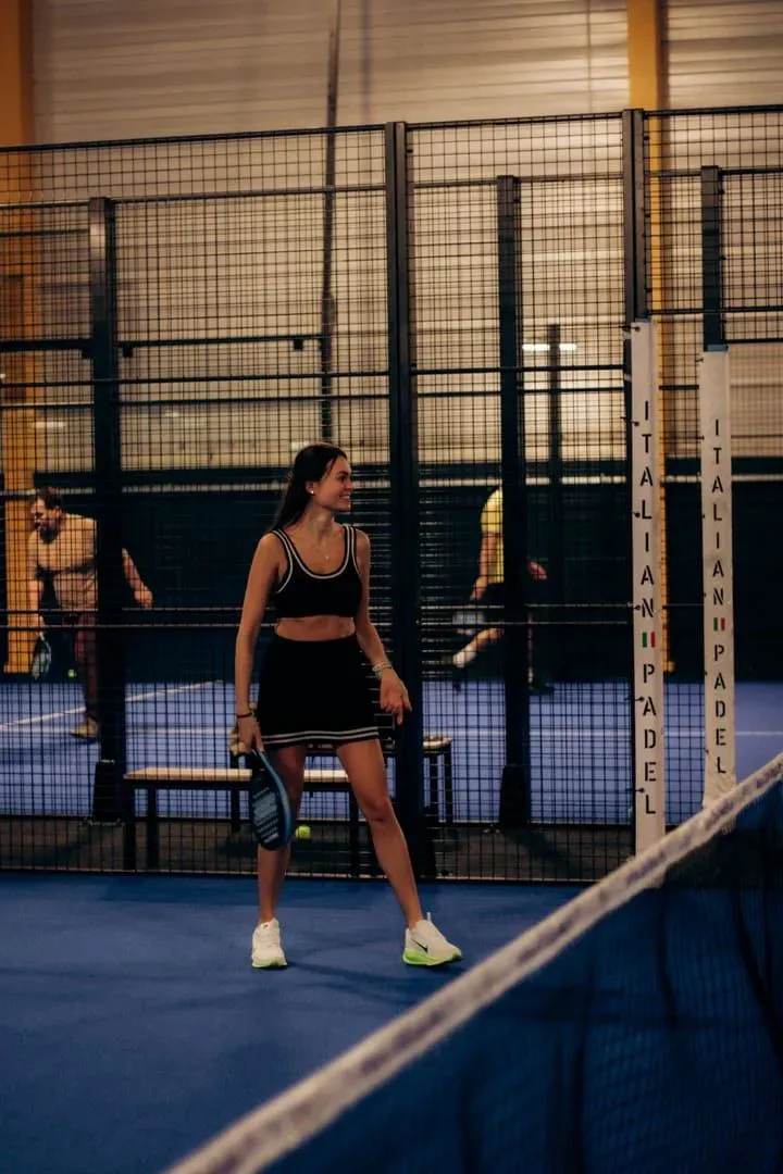 Woman in sports attire playing padel tennis on an indoor court, the covered-court style used at Padel Paradise Lamai