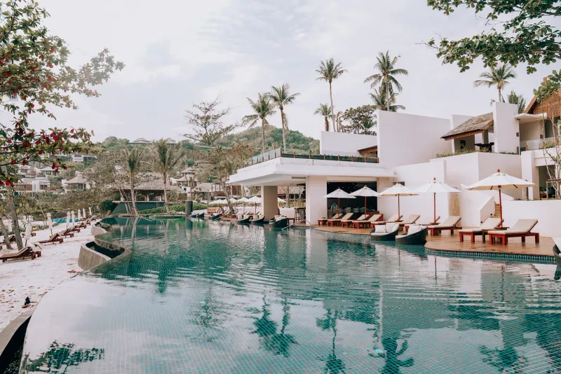 Geschwungener Resortpool mit Poolbar, Liegen und Palmen direkt am Strand des The Ritz-Carlton, Koh Samui