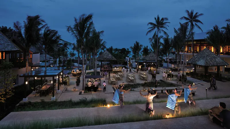 Abendlicher Speisehof mit Essensständen und einer thailändischen Tanzvorführung zwischen Palmen