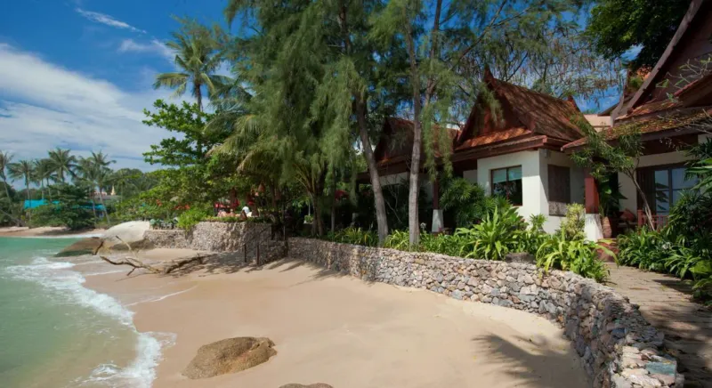 Sandy cove with rocks and a thatched roof villa at Rocky's Boutique Resort on Koh Samui