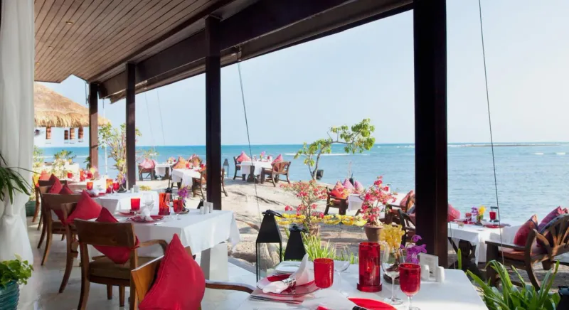 Beachfront dinner tables with red linens and candles by the water at Rocky's Boutique Resort