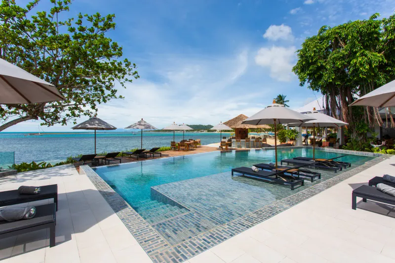 Infinity-edge pool at Rocky's Boutique Resort with loungers and umbrellas above the Gulf of Thailand