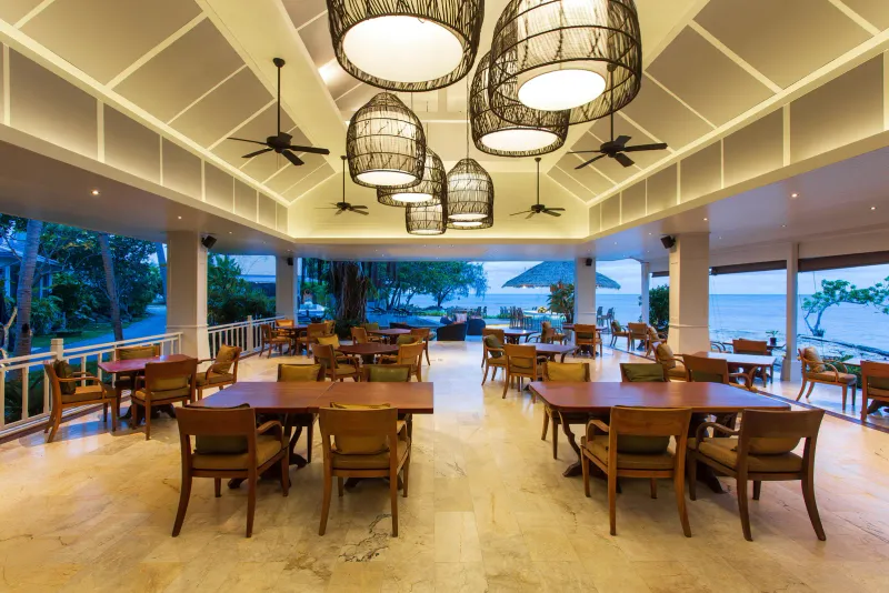 Open dining room at Rocky's Boutique Resort with wooden tables and sea views through wide openings