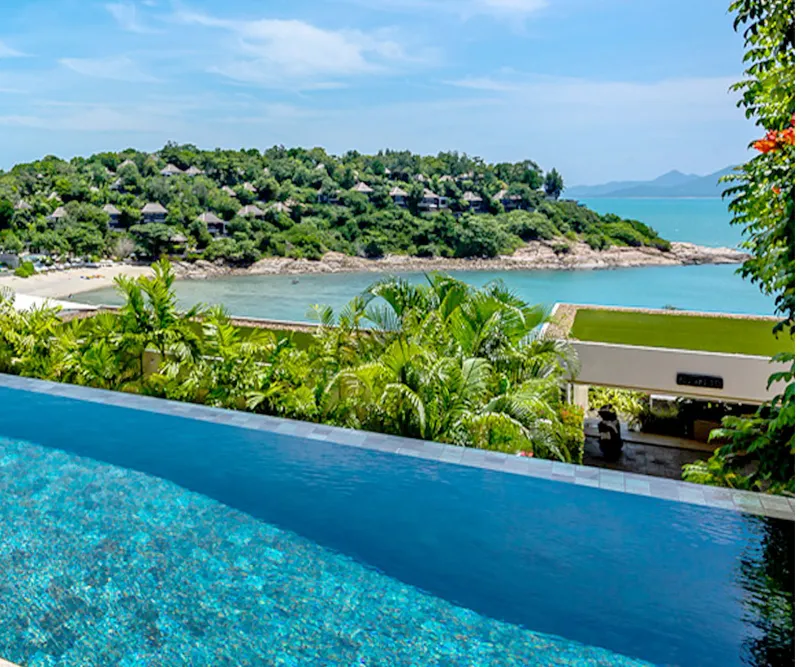 Infinity pool overlooking Samrong Bay from a hillside resort terrace