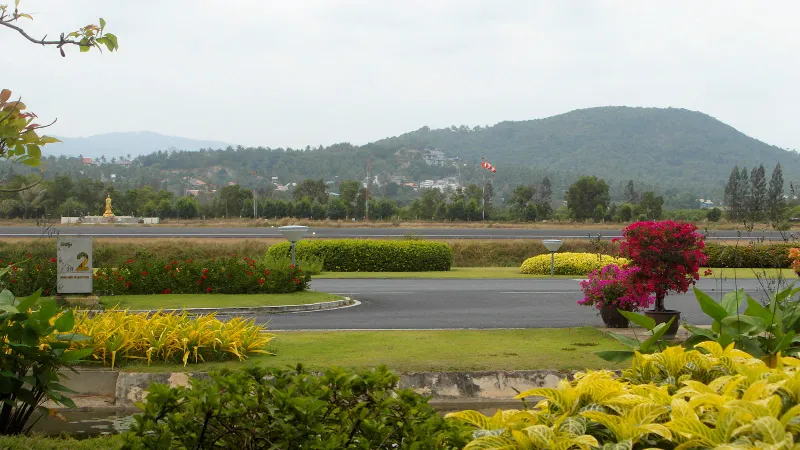 Open-air terminal building at Samui International Airport with palm trees and tiled roofs