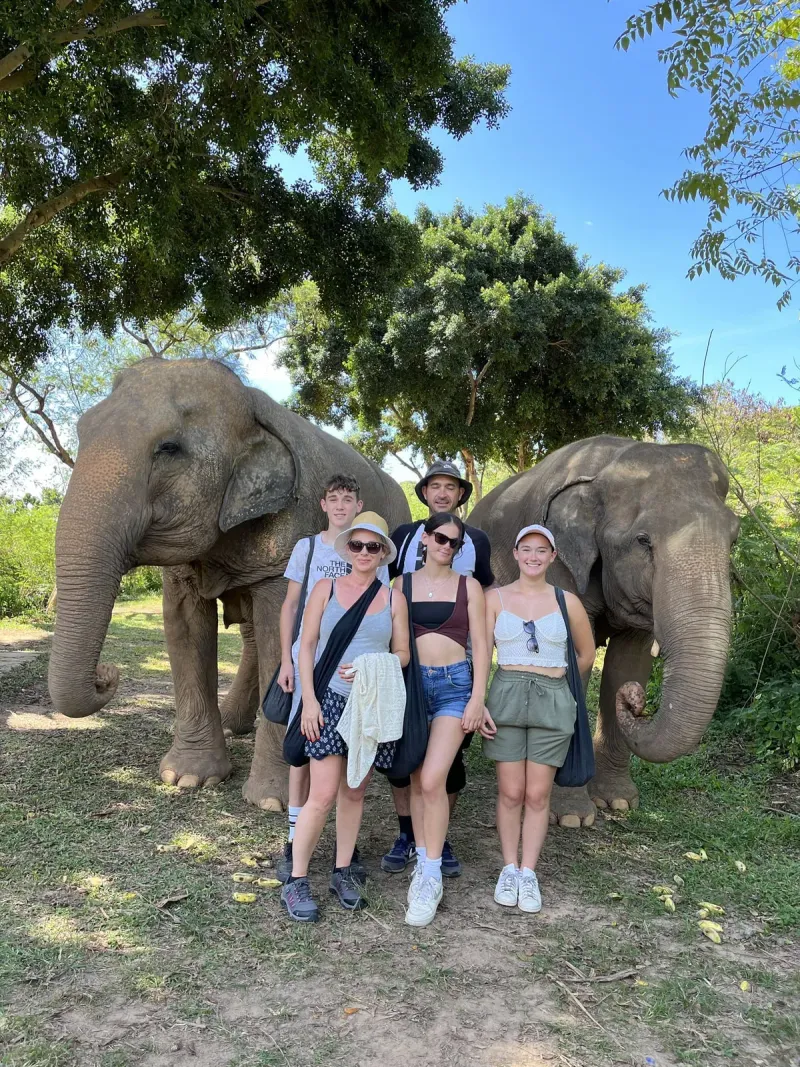 A family standing beside two elephants at Samui Elephant Sanctuary, no saddles or riding gear