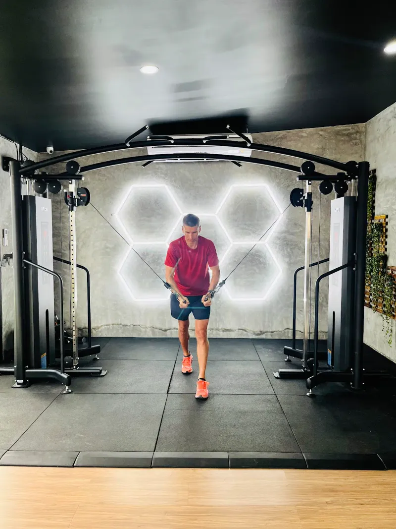 A man using a cable machine under a hexagon light panel