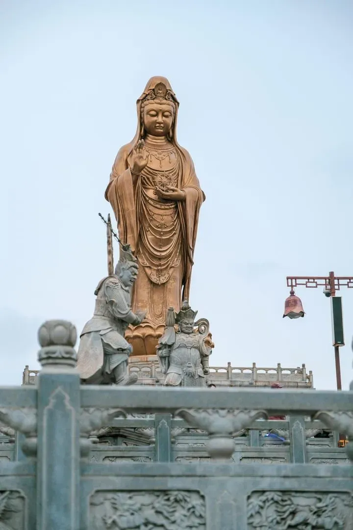 A beautiful statue of Guanyin overlooking a serene temple area, exemplifying tranquility and spiritual grace