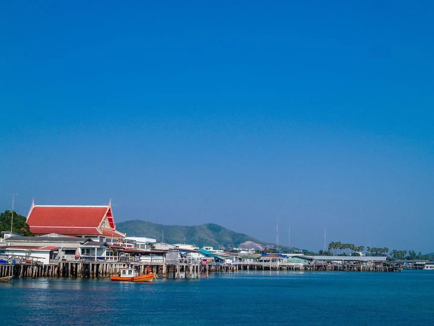Waterfront village on stilts with a red-roofed building and boats