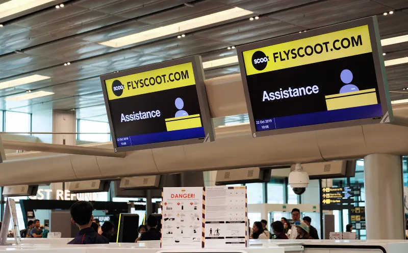 Scoot assistance counter with yellow flyscoot.com signs inside a Singapore Changi terminal