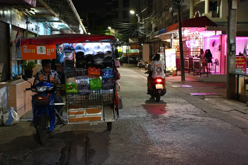 Rider with a young child pillion wearing a bright helmet on a busy Thai street