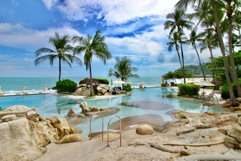 Rock-lined shallow pool with stone turtle sculptures and palms facing the sea at Sheraton Samui Resort