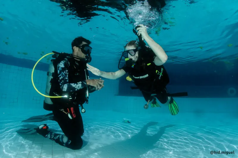 Two divers practising skills near the surface in clear water