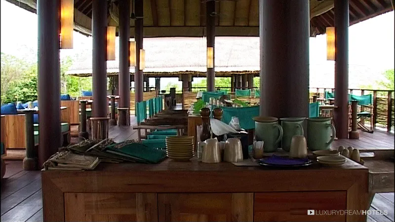 Open-air restaurant at Six Senses Samui with timber columns, a buffet counter and thatched roofs