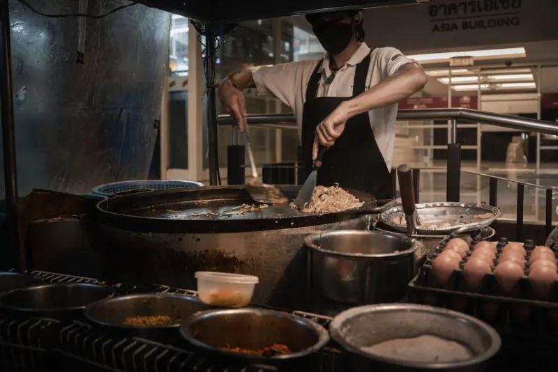 Chef cooking Thai dishes over an open flame, the hands-on style used in Koh Samui classes