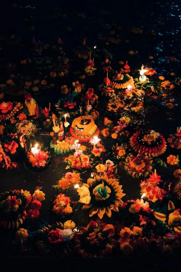 Lebendige schwimmende Blumen- und Kerzenarrangements zu einem buddhistischen Feiertagsfest in Thailand