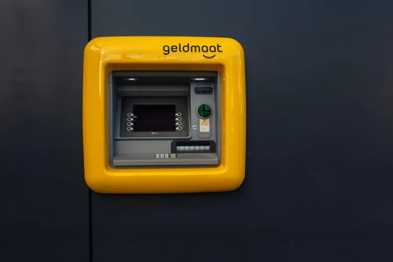 Bright yellow ATM machine mounted on a wall for cash withdrawals in Thailand