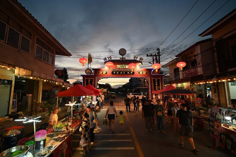 Lantern-lit night market archway with food stalls and evening shoppers, similar to a Koh Samui walking street