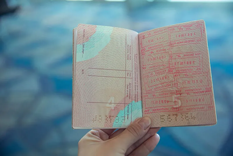 Close-up of an open passport with visa and entry stamps at an airport immigration desk