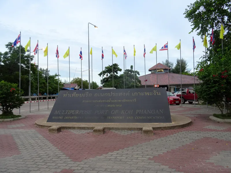 Sign reading Multipurpose Port of Koh Phangan with rows of flags outside the Thong Sala terminal