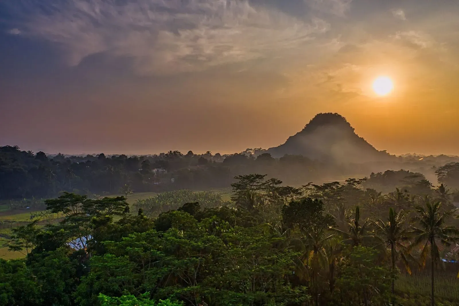 Forested hills silhouetted against a tropical sunset sky, typical of the ridgelines above Koh Samui's coast