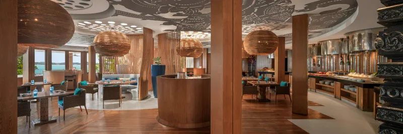 Interior of The Kitchen Table restaurant at W Koh Samui with a patterned ceiling, rattan lamps and a buffet