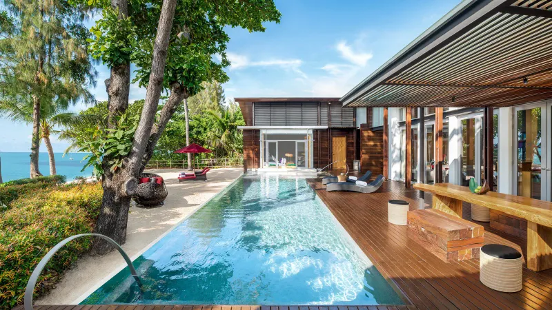 Long plunge pool and timber terrace of a W Koh Samui villa with the sea to the left