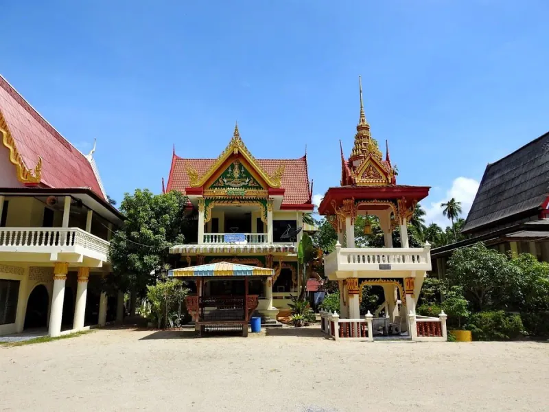 The temple's two-storey pavilion and small bell tower on a sandy courtyard