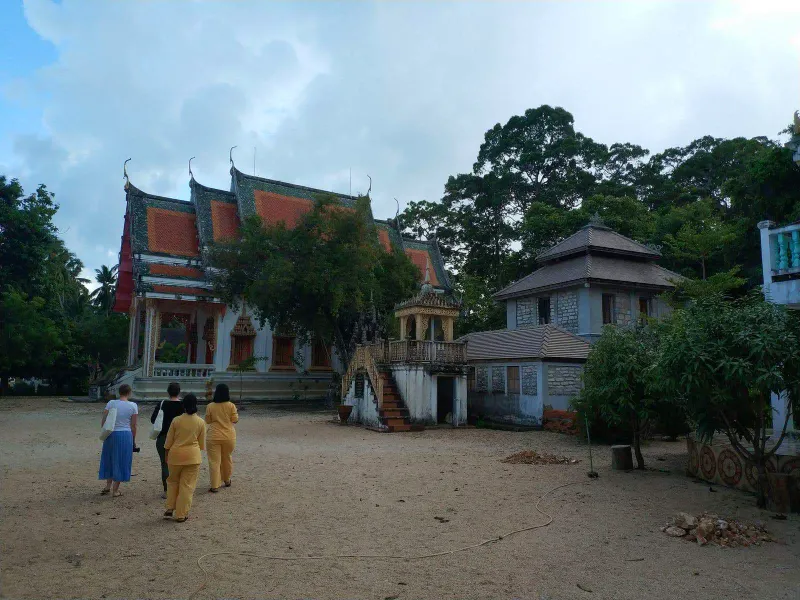 Visitors walking across the sandy temple courtyard toward the main hall at dusk