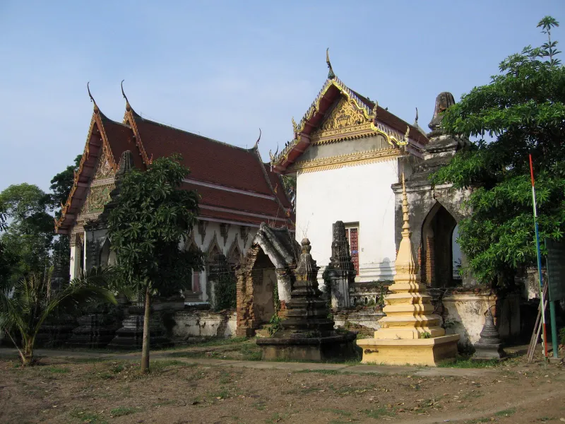 Weathered old temple ruins with a small yellow chedi beside a red-roofed hall on Koh Samui
