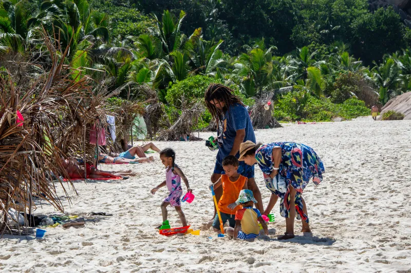 A family building in the sand under palm trees